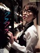 A woman wearing glasses standing in front of a wine rack.