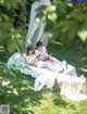 A couple of women laying on top of a bed in the grass.