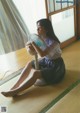 A woman sitting on the floor with a fan in her hand.