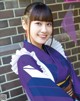 A woman in a purple and white kimono posing for a picture.