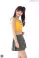 A woman in a yellow top and a green skirt.