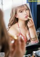 A woman applying lipstick in front of a mirror.